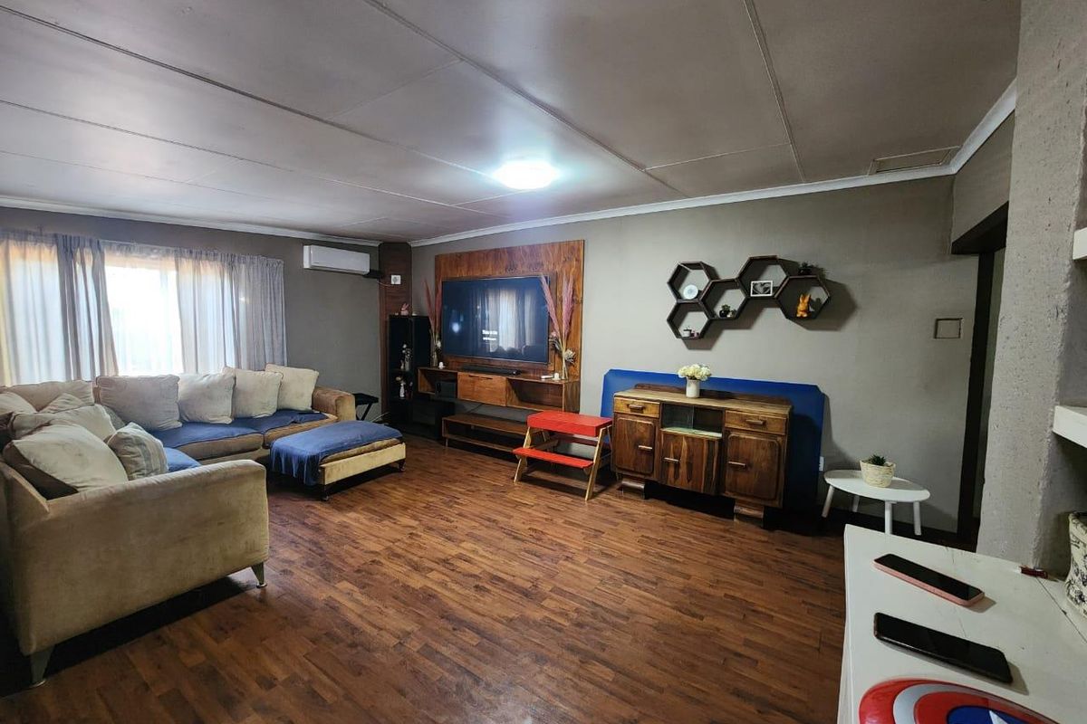 Spacious living room featuring wood-look flooring, a built-in media unit, and a wall-mounted air conditioning unit.