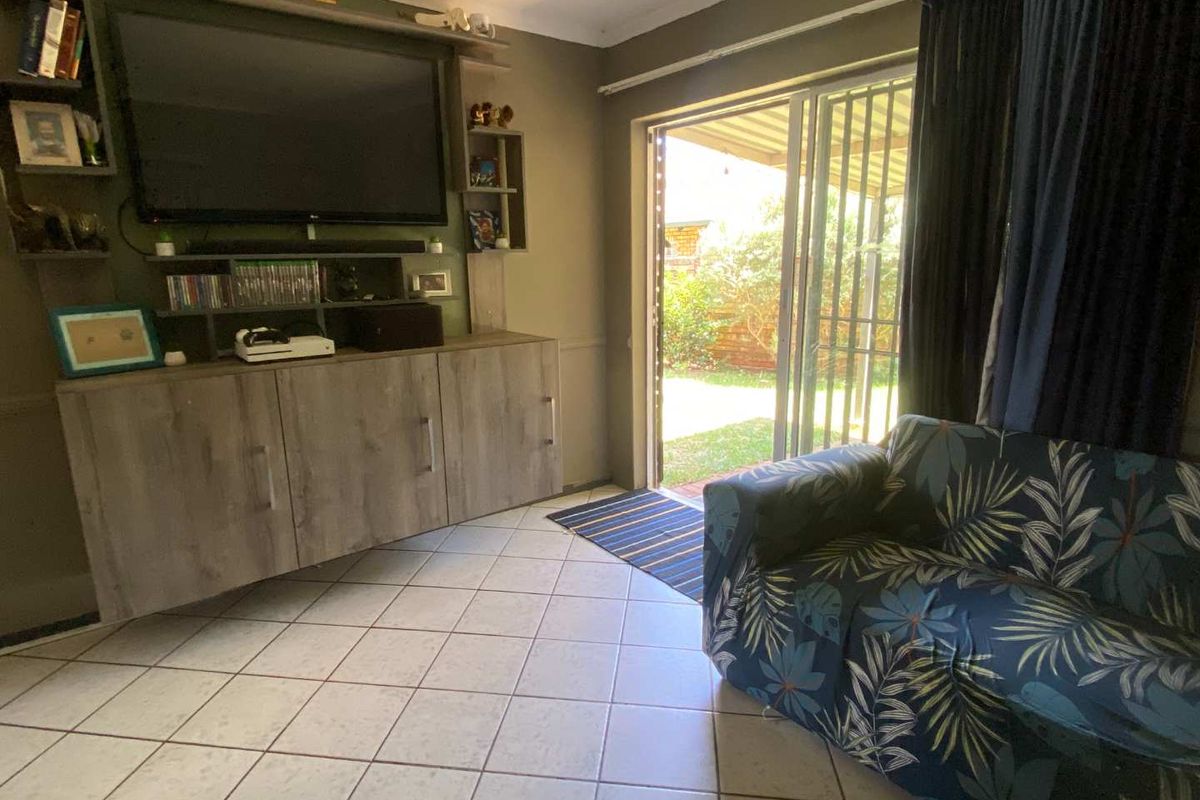 Living room featuring tiled flooring and built-in cabinetry, with sliding glass doors providing direct access to the rear garden area.