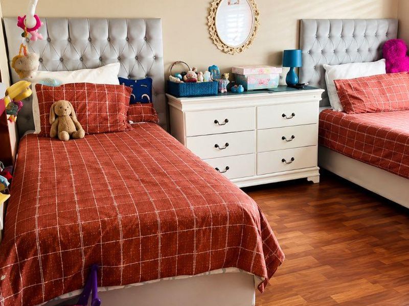A well-maintained bedroom featuring warm-toned laminate flooring and neutral wall finishes, providing a comfortable and functional living space.