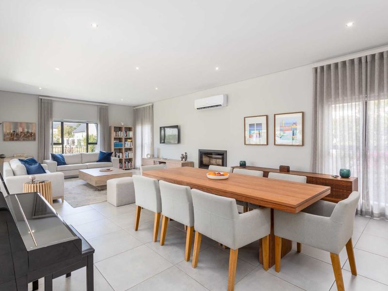 Spacious open-plan living and dining area featuring tiled floors, recessed lighting, a built-in fireplace, and split-system air conditioning with access to outdoor space.