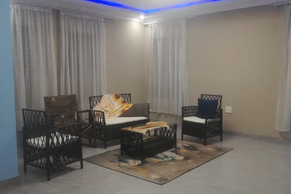 A living room featuring tiled flooring, recessed ceiling lighting with blue accent strips, and large windows with sheer curtains.