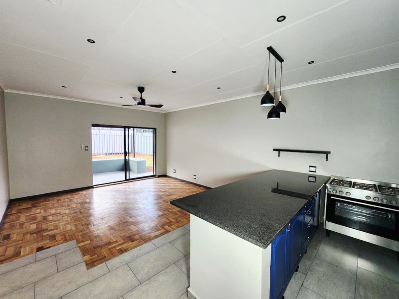 Spacious open-plan living area featuring a modern kitchen with a granite island, gas stove, parquet and tiled flooring, and direct access to the patio.