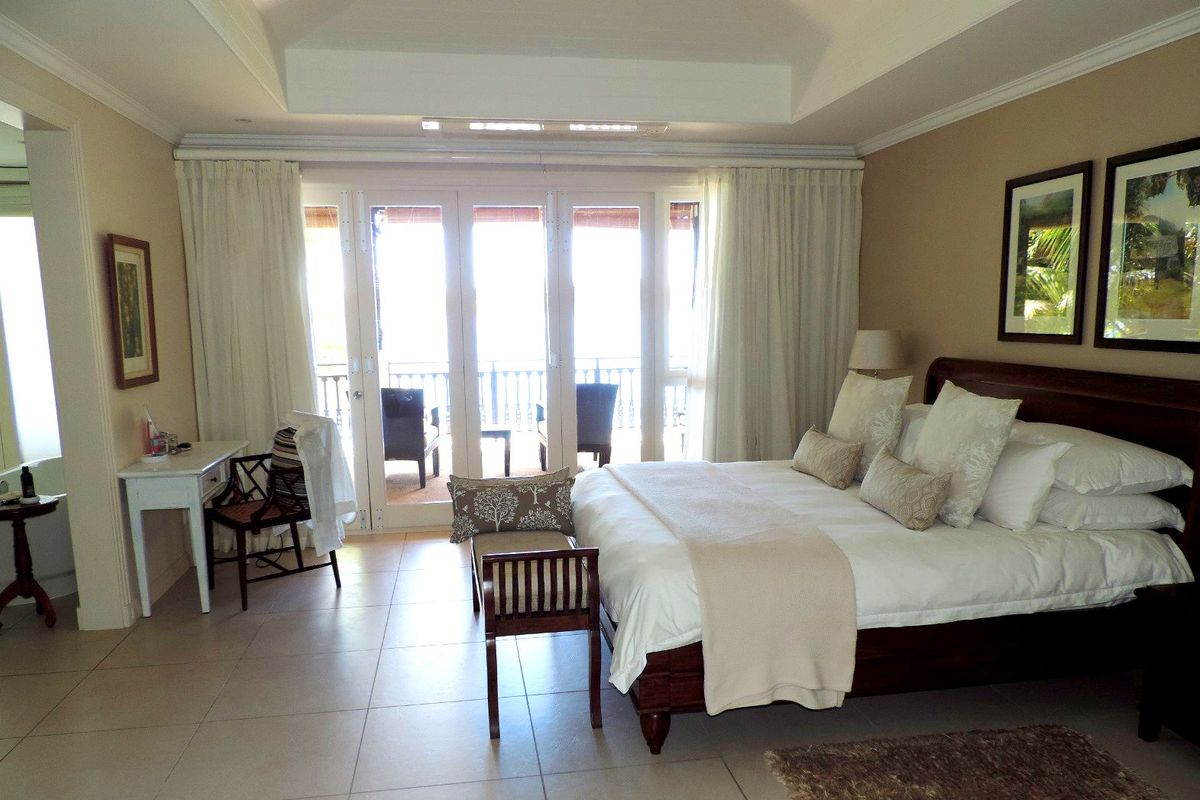 Spacious bedroom featuring a tray ceiling, tiled flooring, and large glass sliding doors opening onto a private balcony with scenic views.