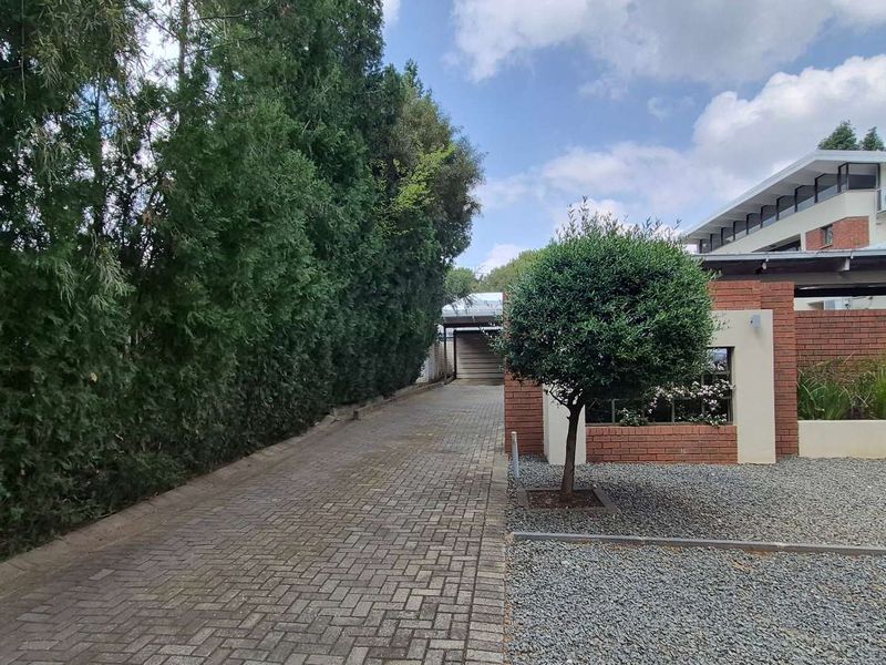 A well-maintained office property exterior featuring a paved driveway, brick facade, and neat landscaping.