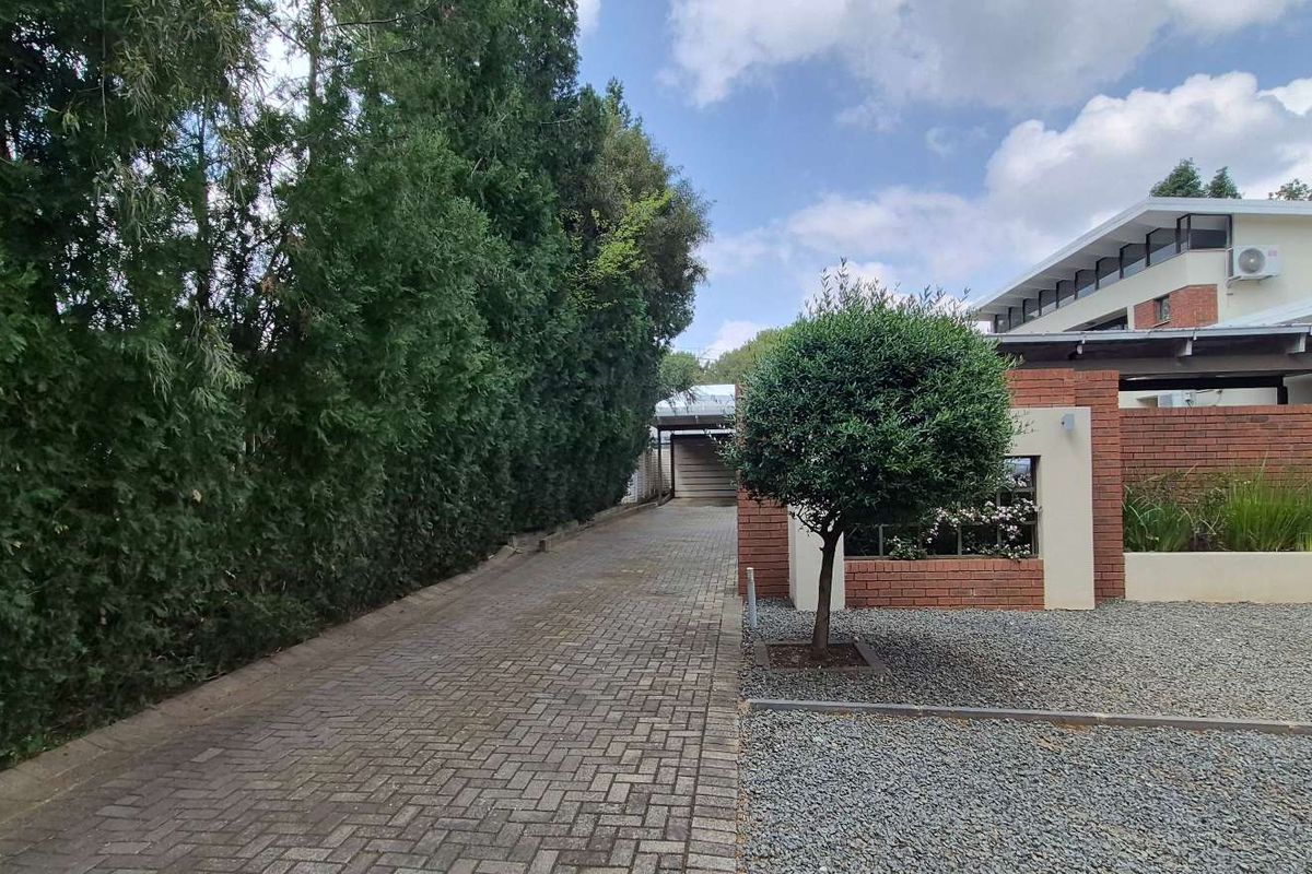 A well-maintained office property exterior featuring a paved driveway, brick facade, and neat landscaping.