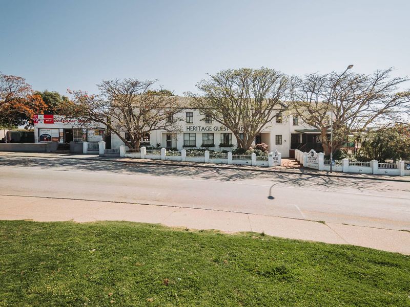 Front exterior view of the Heritage Guest House, showcasing the building facade, perimeter fencing, and street-facing entrance.