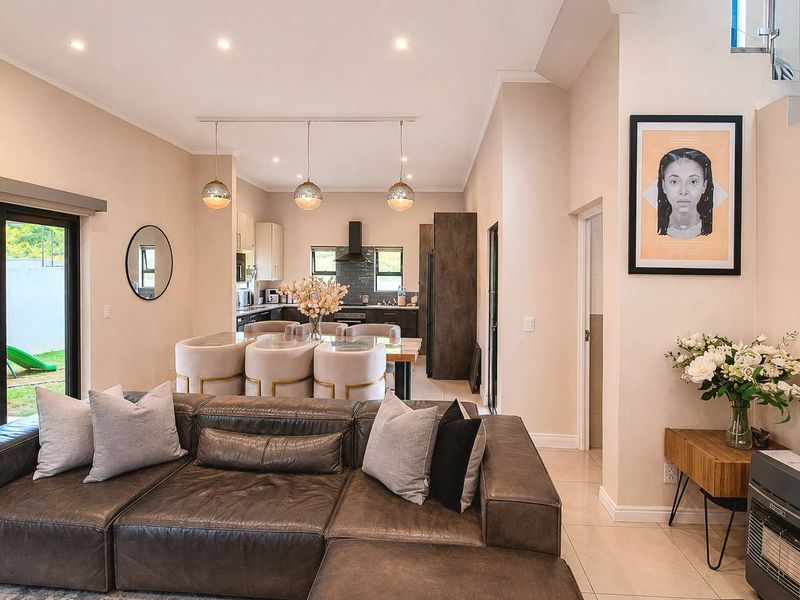 Spacious open-plan living and dining area featuring modern tiled floors, recessed lighting, and seamless flow to the outdoor patio through large sliding glass doors.