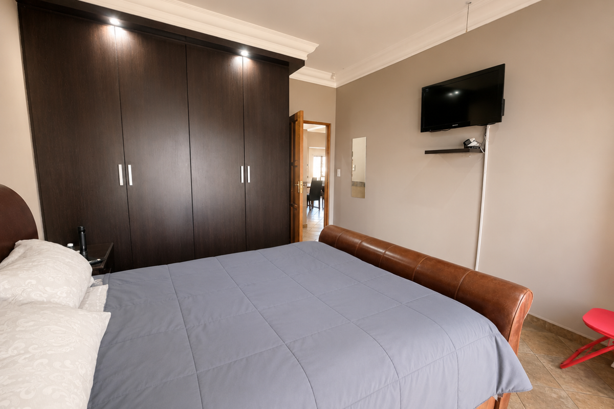 A well-maintained bedroom featuring dark wood built-in cupboards, recessed lighting, crown molding, and tiled flooring.