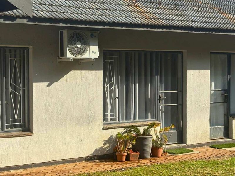 Rear exterior view of the house featuring a tiled roof, security gates, and an installed air conditioning unit with brick paved walkway.