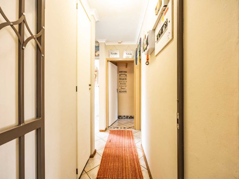 A functional hallway featuring tiled flooring, built-in storage cupboards, and a security gate, providing access to other areas of the home.