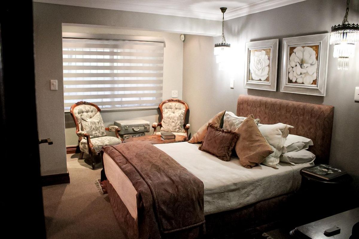 A well-maintained bedroom featuring neutral wall tones, carpeted flooring, and modern window blinds, providing a comfortable and inviting living space.