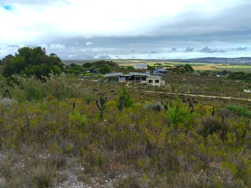 A scenic elevated view of the residential property set within a natural landscape, showcasing the surrounding terrain and distant horizon.