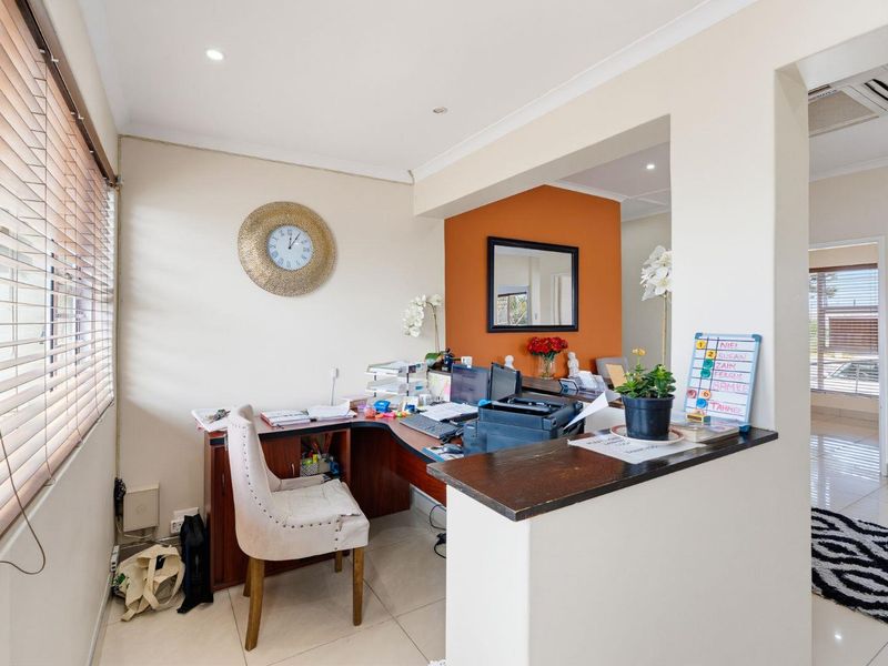 A functional office space featuring tiled flooring, recessed lighting, an integrated desk area, and air conditioning, providing a professional work environment.