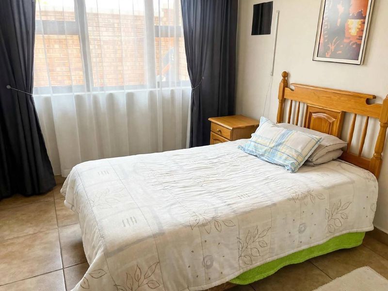 A functional bedroom featuring tiled flooring and a large window that allows for natural light.