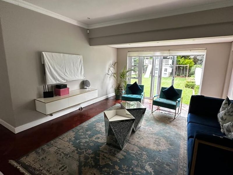 A bright living room featuring hardwood flooring, recessed lighting, and large sliding glass doors that provide direct access to the rear garden.