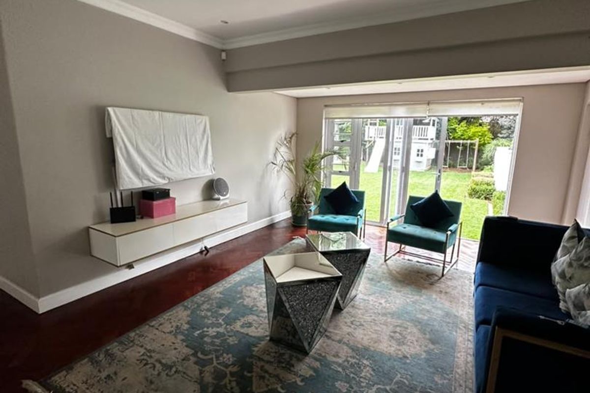 A bright living room featuring hardwood flooring, recessed lighting, and large sliding glass doors that provide direct access to the rear garden.