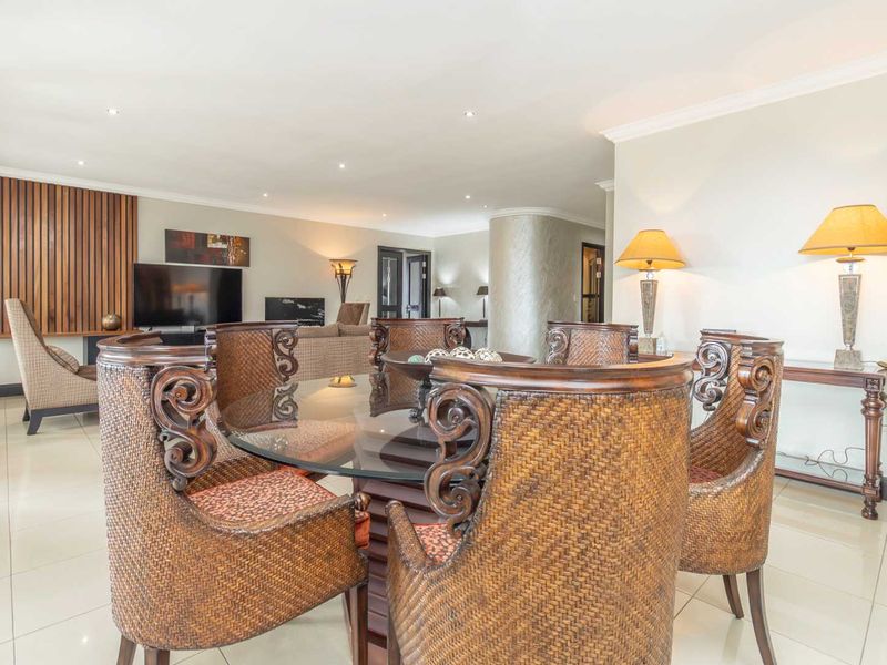 Spacious open-plan living and dining area featuring polished porcelain tiles, recessed lighting, and a decorative timber slat wall feature.