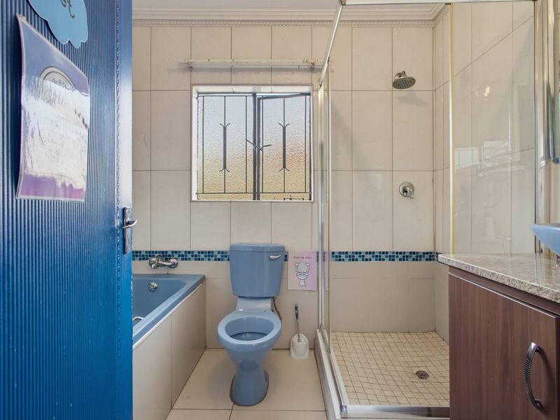 A functional bathroom featuring a built-in vanity with granite countertop, a separate shower enclosure, a bathtub, and a toilet with tiled wall finishes.