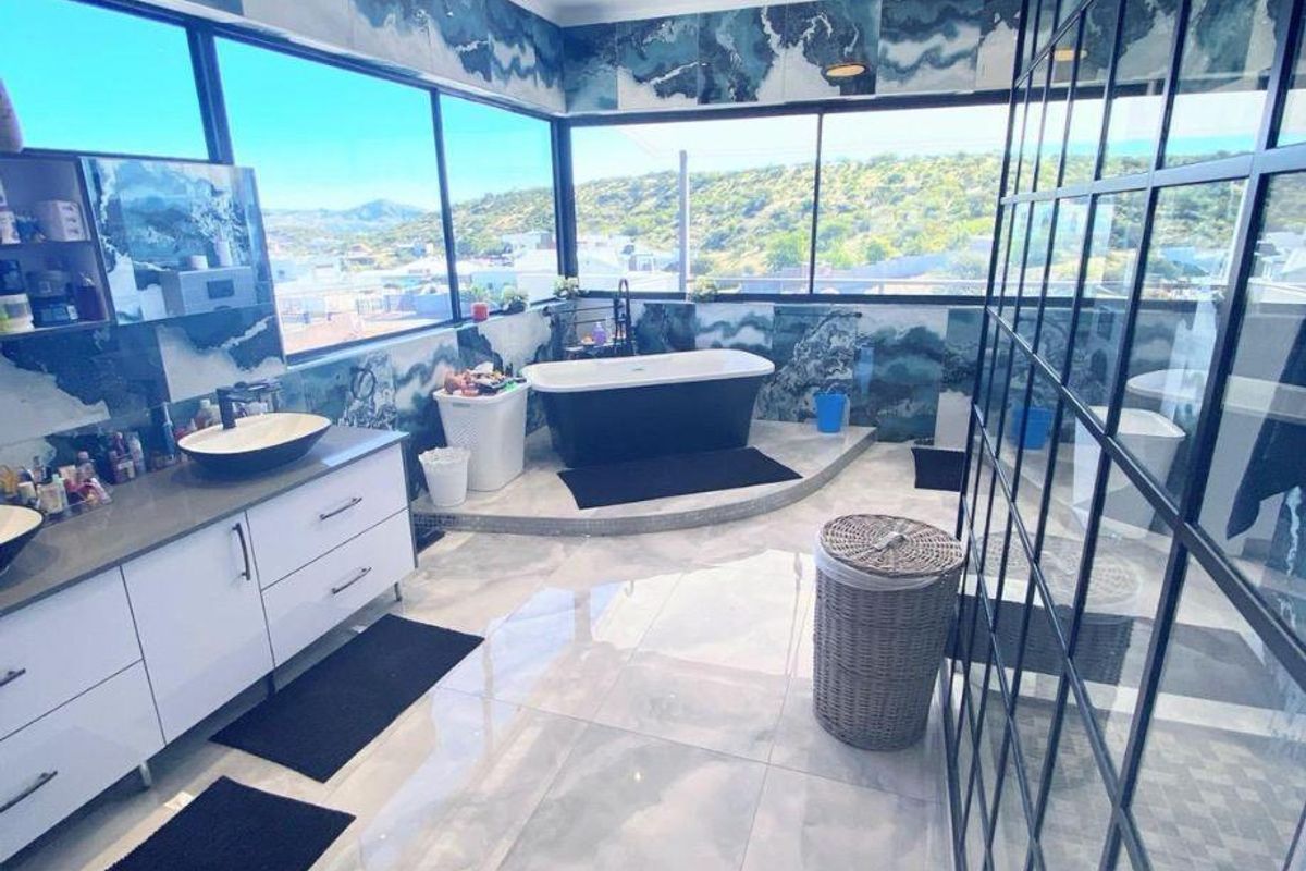 Modern, spacious bathroom featuring a freestanding bathtub, dual vanity with vessel sinks, large windows with panoramic views, and a walk-in glass shower enclosure.