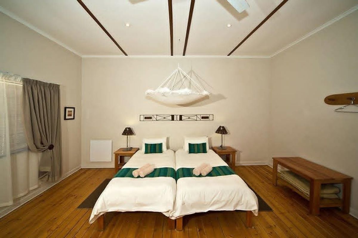 A well-maintained hotel bedroom featuring polished wooden flooring, decorative ceiling beams, and neutral wall finishes, providing a comfortable and inviting guest space.