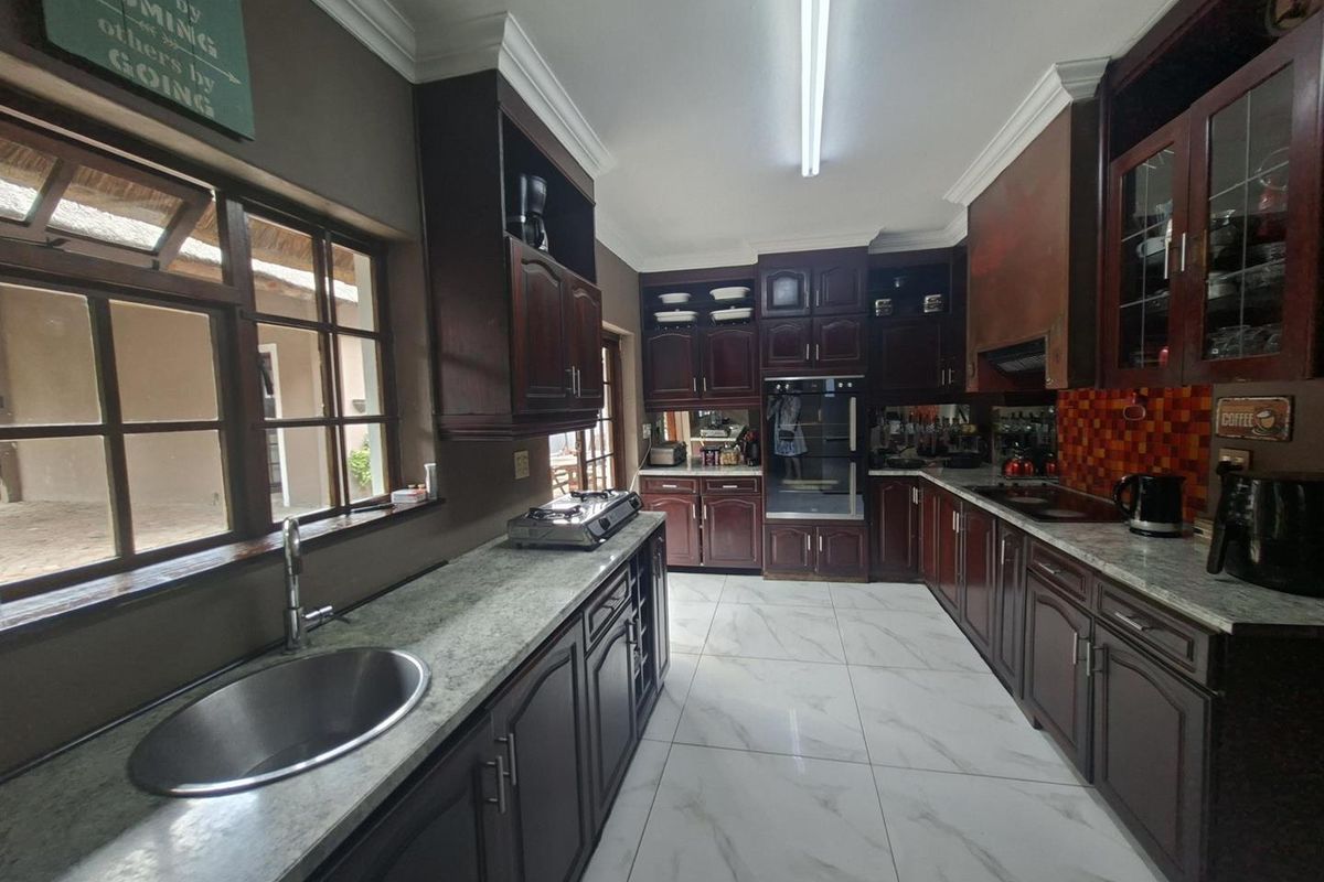 Spacious kitchen featuring dark wood cabinetry, granite countertops, tiled flooring, and integrated oven, offering a functional layout with ample storage and workspace.