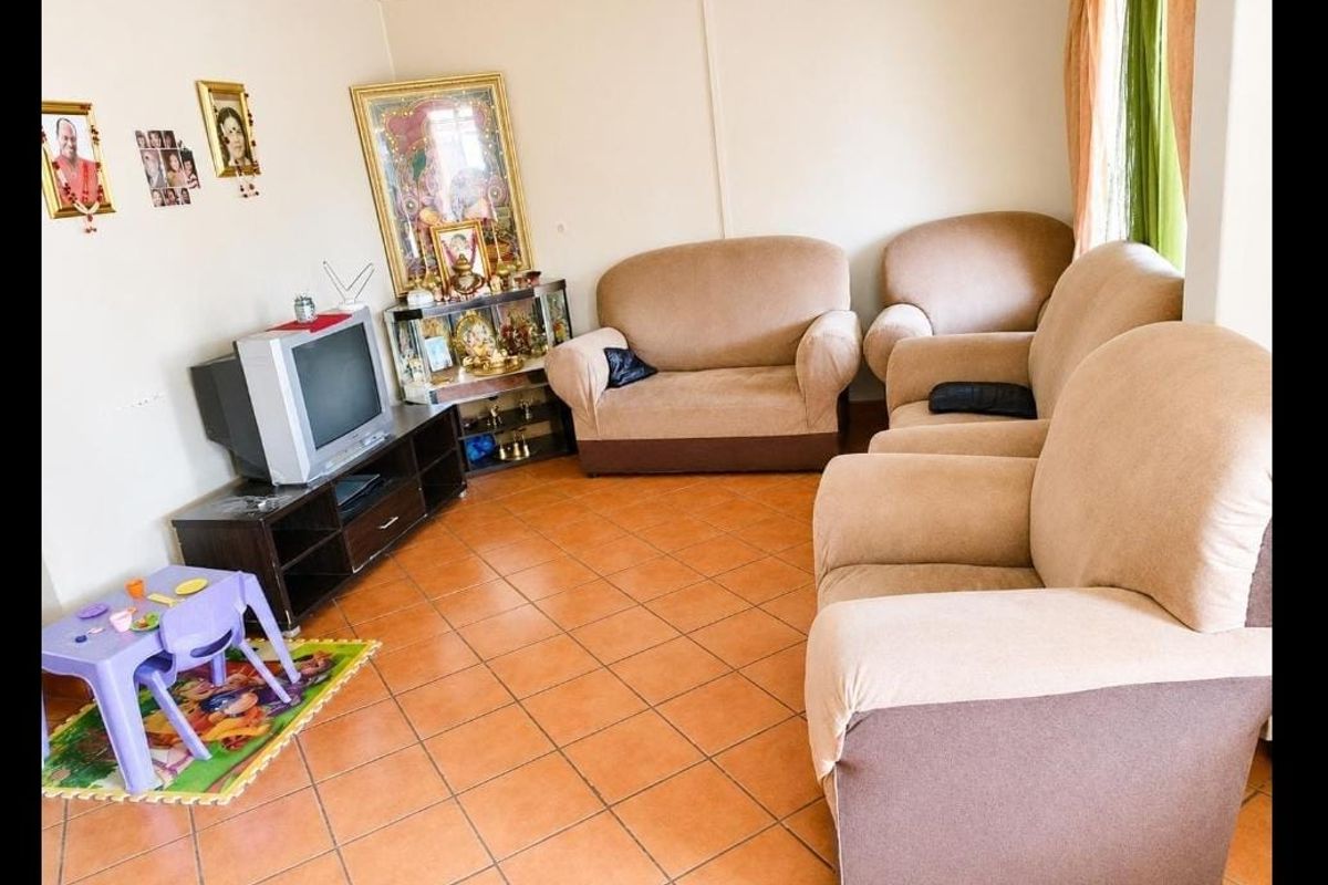 A living room area featuring tiled flooring and coved ceiling details, providing a functional space for relaxation.