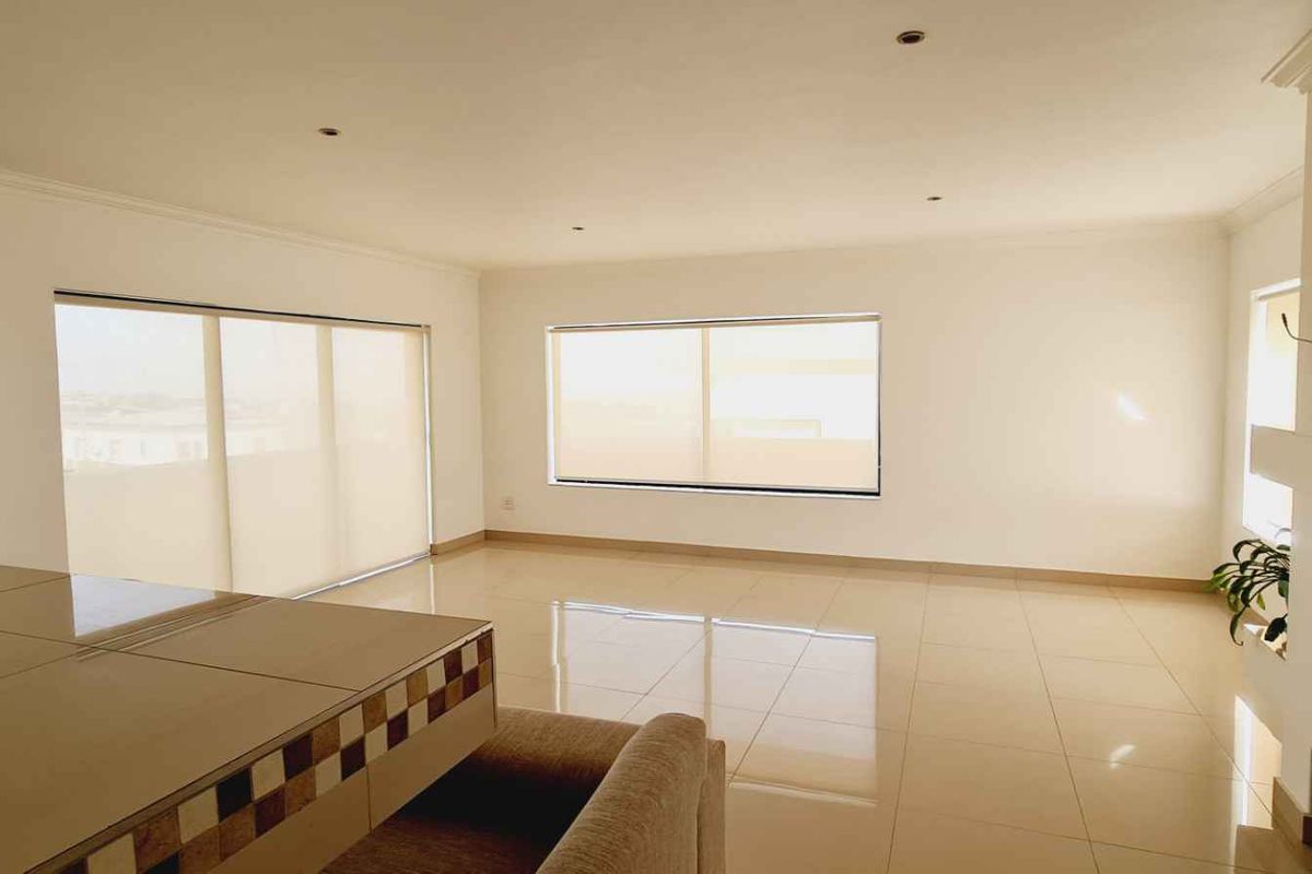 Spacious, light-filled living area featuring neutral tiled flooring, a built-in fireplace, and large sliding glass doors with roller blinds.