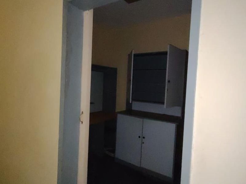 A small utility or storage room featuring built-in cabinetry and basic lighting, currently vacant and in need of cosmetic updates.