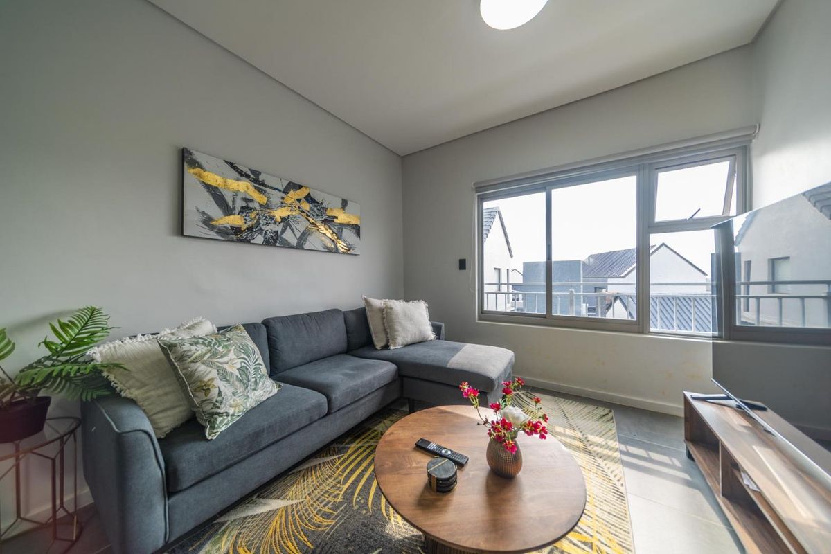 A comfortable living room featuring tiled flooring and a large sliding window that provides natural light and views of the surrounding cluster complex.