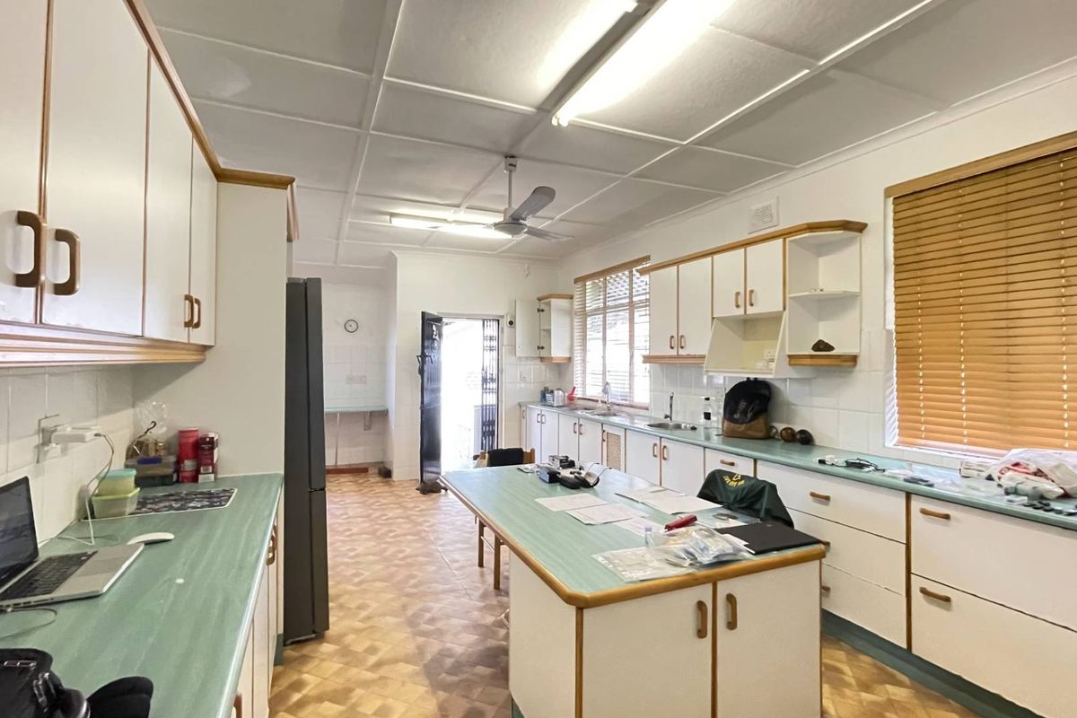 Spacious kitchen featuring extensive laminate countertops, ample built-in cabinetry, double sink, and functional layout with direct access to the exterior.