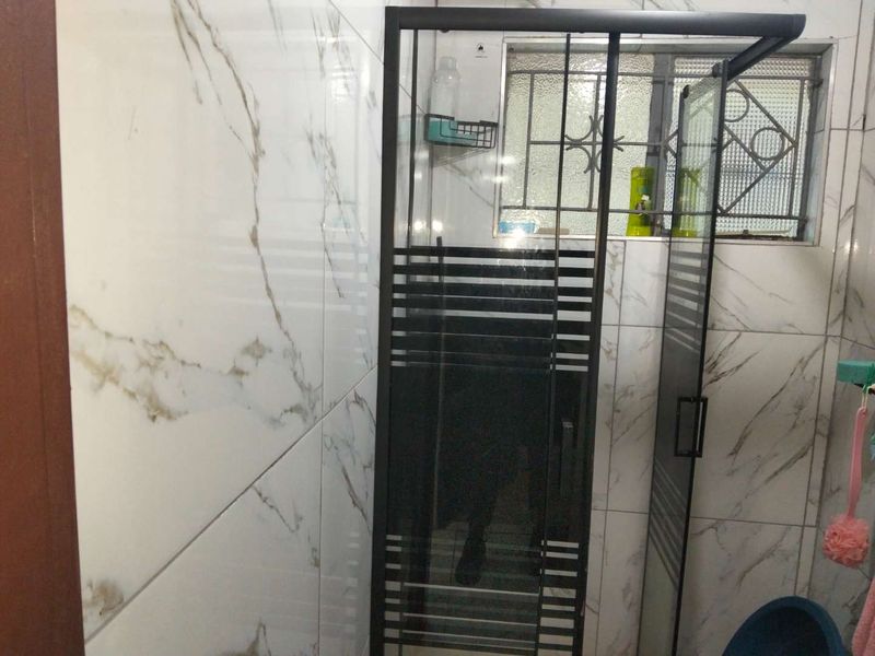 A bathroom featuring a modern shower enclosure with black framing and marble-look wall tiles.