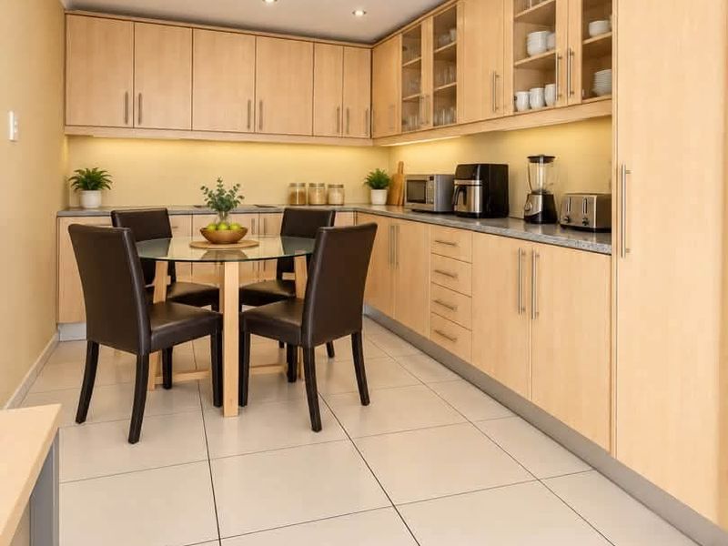 A well-maintained kitchen featuring light-wood cabinetry, stone-look countertops, under-cabinet lighting, and modern tiled flooring, offering a clean and functional workspace.