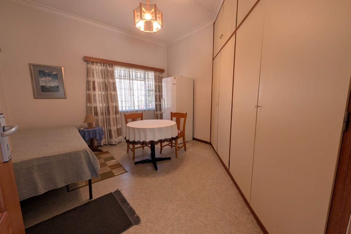A bedroom featuring extensive floor-to-ceiling built-in cupboards and coved cornicing, offering functional storage space in a neutral setting.