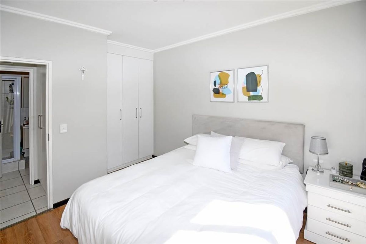 A well-maintained bedroom featuring laminate flooring, built-in cupboards, and direct access to an en-suite bathroom.