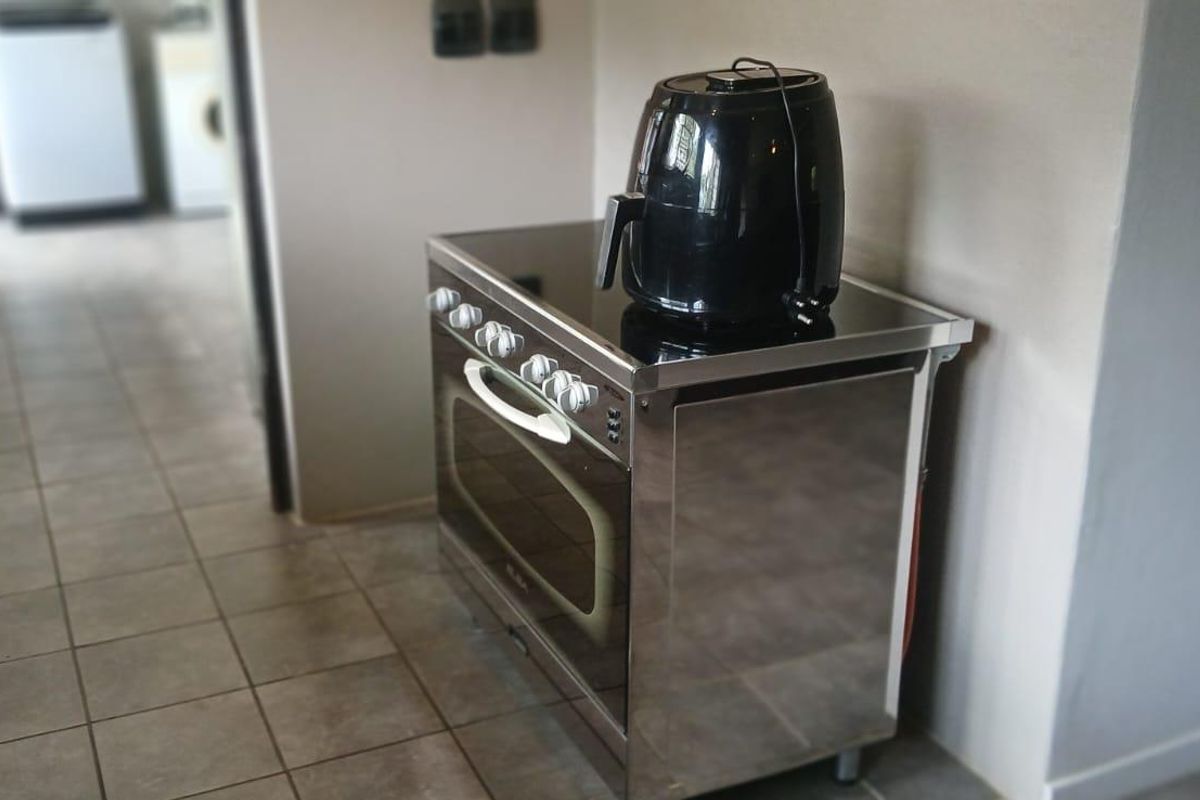 A kitchen area featuring a freestanding stainless steel oven and stove, with tiled flooring and a view into an adjacent utility space.