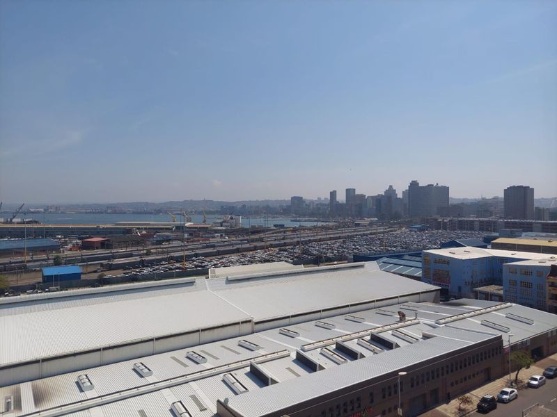 Elevated urban view overlooking industrial port facilities, railway infrastructure, and the distant city skyline.