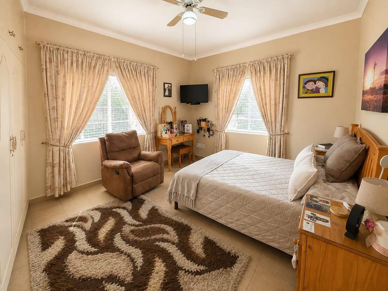 A well-maintained bedroom featuring tiled flooring, built-in cupboards, and a ceiling fan, offering a comfortable and functional living space.