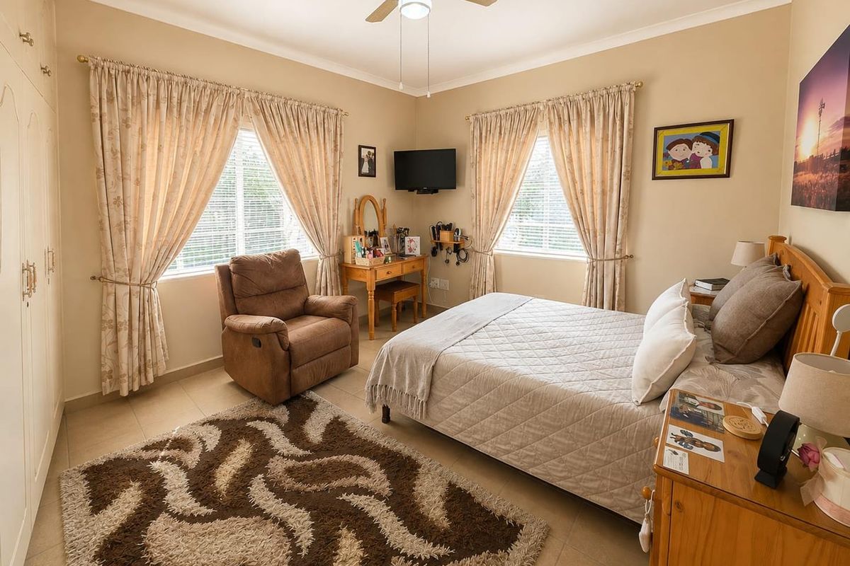 A well-maintained bedroom featuring tiled flooring, built-in cupboards, and a ceiling fan, offering a comfortable and functional living space.