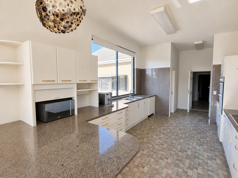 Spacious kitchen featuring granite countertops, ample built-in cabinetry, integrated appliances, and a functional layout with a dedicated appliance garage.