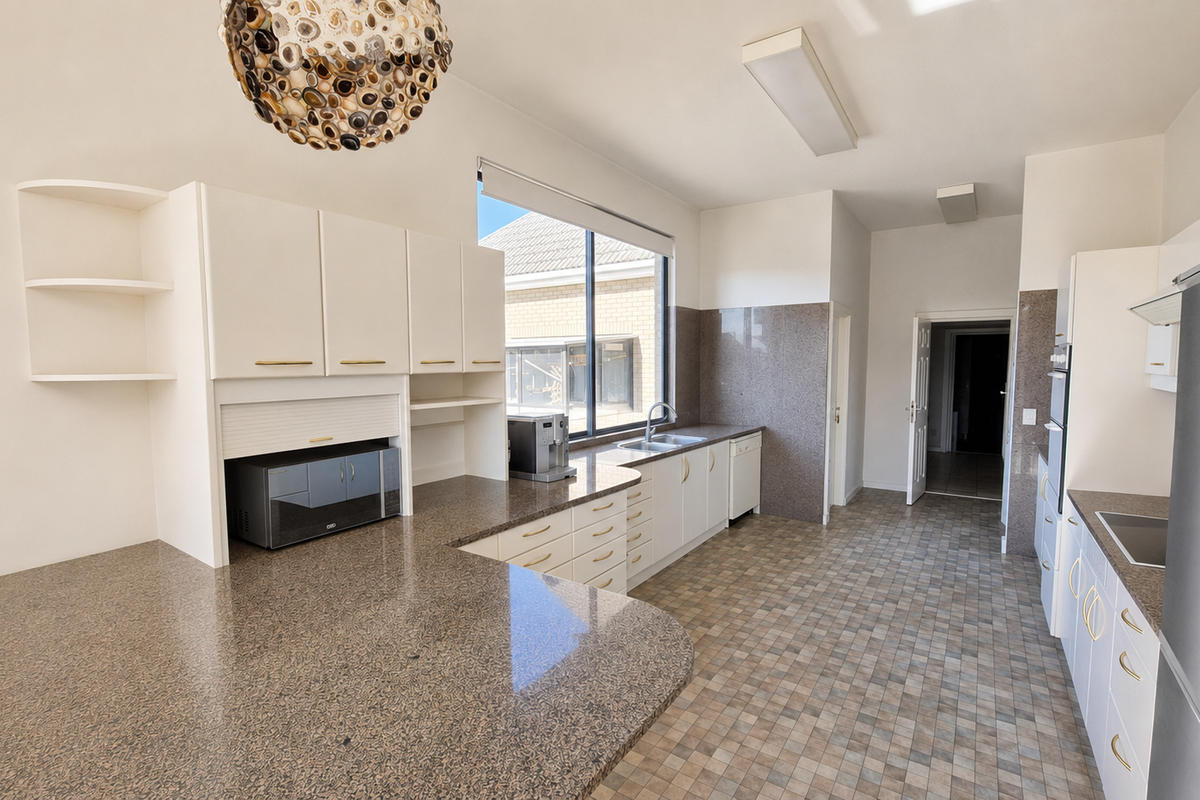 Spacious kitchen featuring granite countertops, ample built-in cabinetry, integrated appliances, and a functional layout with a dedicated appliance garage.