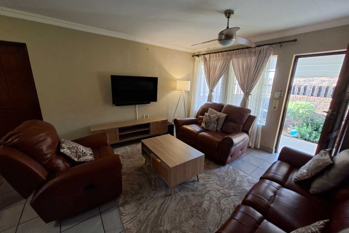 A comfortable living room featuring tiled flooring, a ceiling fan, and direct access to an outdoor patio area through a sliding glass door.