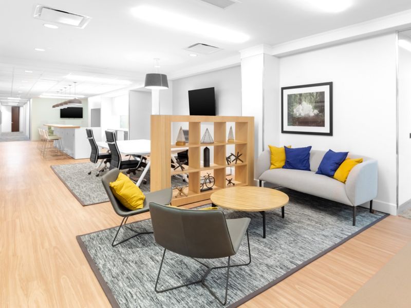 Modern open-plan office space featuring a lounge area, integrated kitchen counter, and professional finishes with bright, recessed lighting throughout.