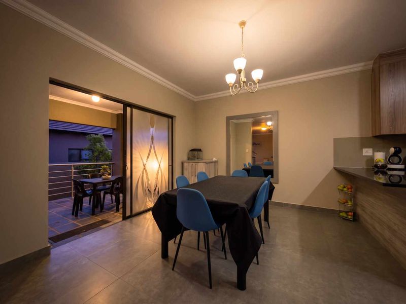 Open plan dining area featuring tiled floors, modern cabinetry, and a sliding glass door leading to an outdoor patio space.