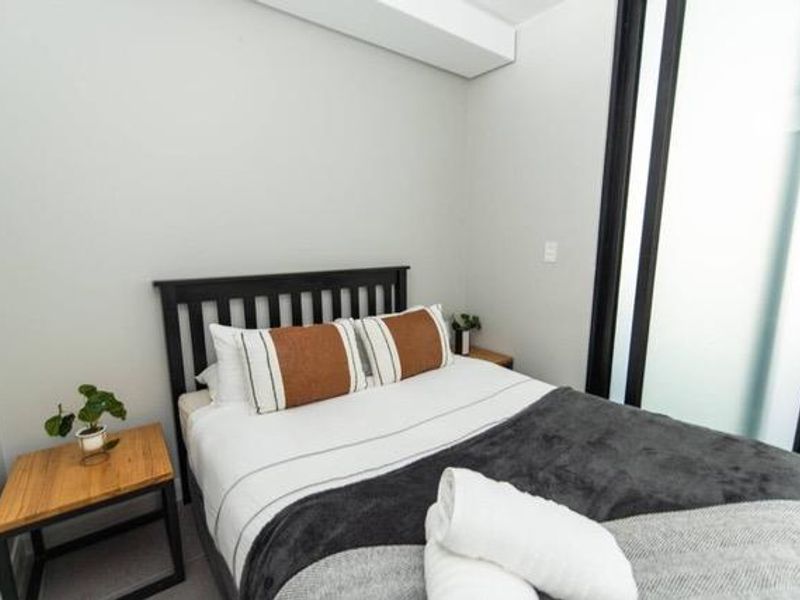 A modern bedroom featuring neutral walls and a contemporary sliding glass door, providing a clean and minimalist living space.