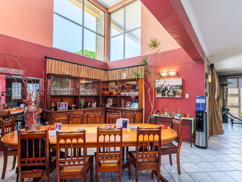 Spacious dining area featuring double-volume ceilings, large windows for natural light, and tiled flooring, creating an open and airy atmosphere.