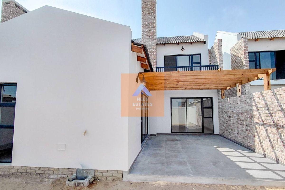 Rear view of the townhouse featuring a tiled patio with a timber pergola, sliding glass doors, and an upper-level balcony.
