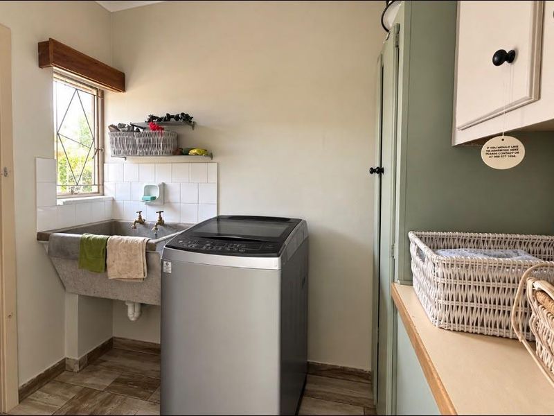 Functional laundry room featuring a concrete utility sink, built-in cabinetry, and tiled flooring with a window for natural light.