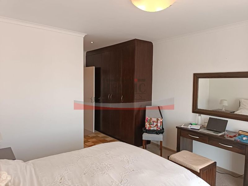 A bedroom featuring dark wood built-in cupboards and neutral wall finishes.