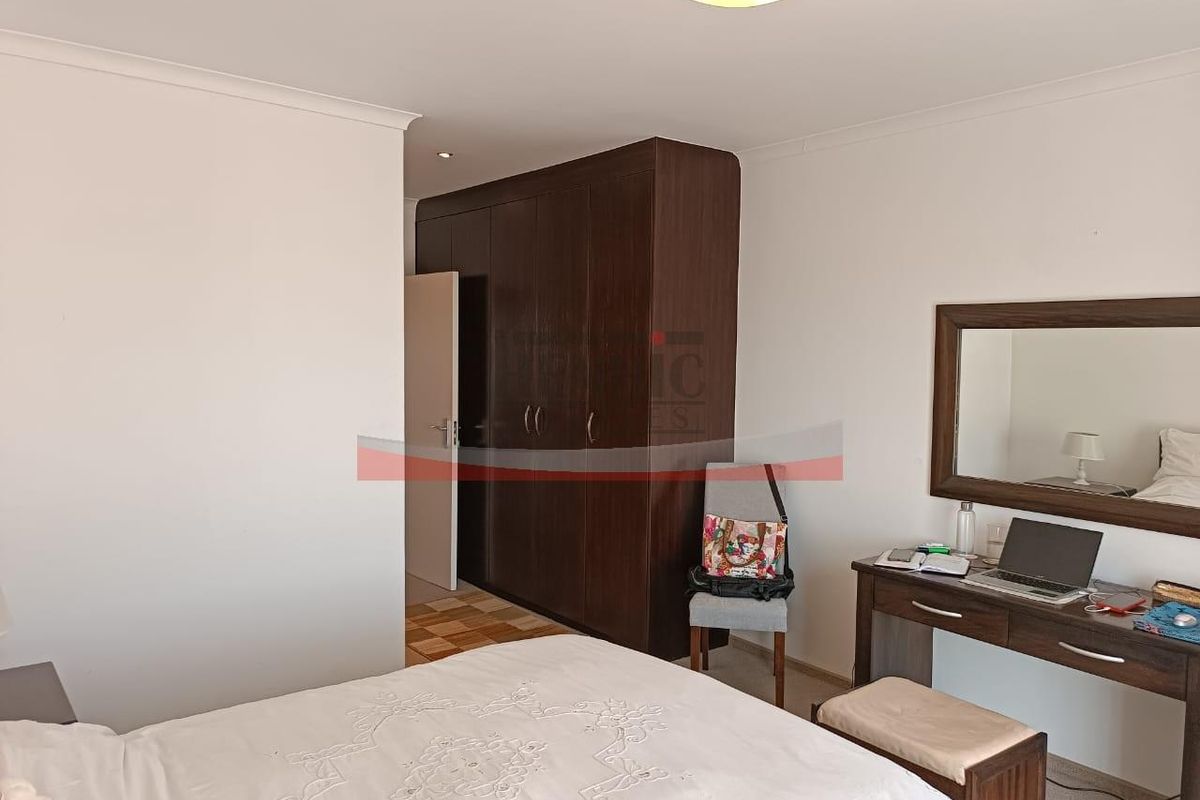 A bedroom featuring dark wood built-in cupboards and neutral wall finishes.