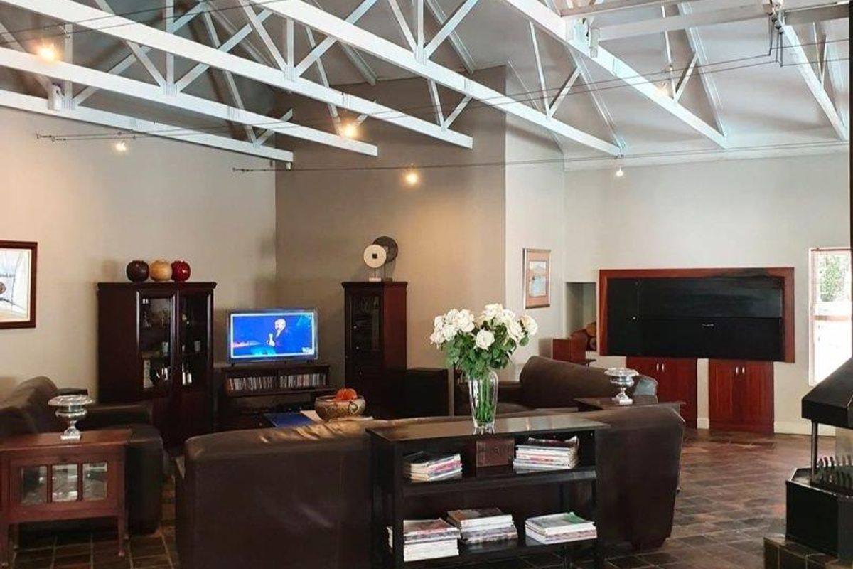 Spacious living area featuring high vaulted ceilings with exposed white trusses, slate tile flooring, and a built-in fireplace.